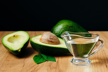 Avocado oil and ripe fresh avocado on wooden table on wooden table, close-up