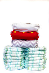 Reusable cloth diapers and single use disposable diapers on white background