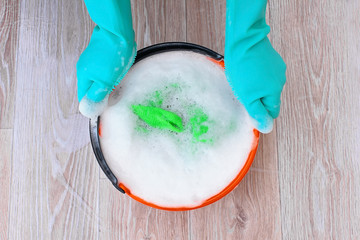 Wet cleaning and laundry. Hands hold, carries a bucket of soapy foamy water.