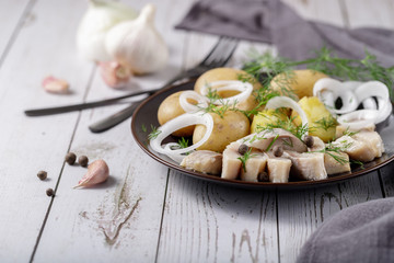 Traditional scandinavian food: salted herring slices with boiled potatoes and fresh raw onions.