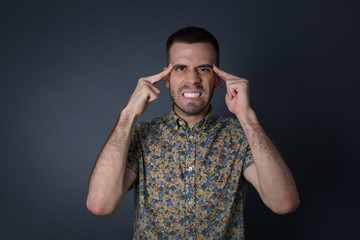 Young handsome caucasian man concentrating hard on an idea, with a serious look, thinking with both index fingers pointing to forehead eyes closed.