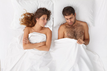 Relationship difficulties, impotence concept. Stressed married couple have marital problems because of mans erectile dysfunction, problems with man health, pose in bedroom. Intimacy troubles. - obrazy, fototapety, plakaty