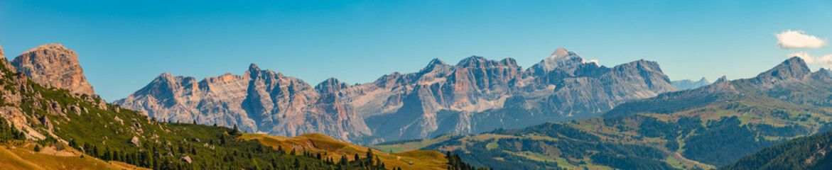Panoramic view made from Passo Gardena of magical Dolomite peaks of Cima Cunturines in sunset colors at blue sky, South Tyrol, Italy, wide angle