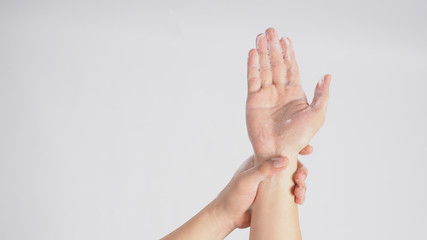 Male model is rub wrist to mid-upper arm in a rotating manner with foaming hand soap on white background.