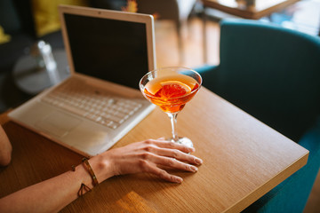 A glass of margarita cocktails and a laptop on the table