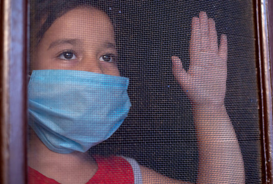 girl in mask looking outside from the door net in hope of 
free from the corona virus /Covid-19  Virus