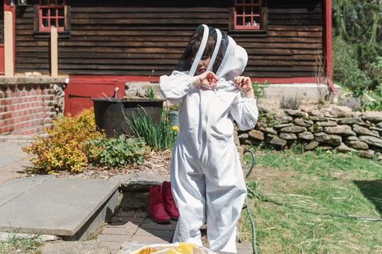 little girl getting dressed in apiarist suit to check on beehive