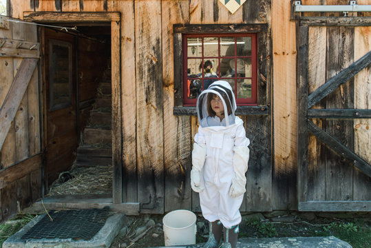 little girl getting dressed in apiarist suit to check on beehive