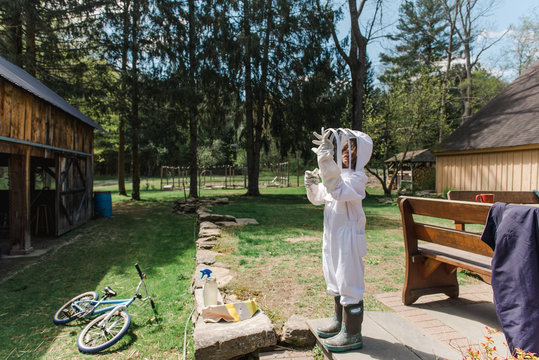 little girl getting dressed in apiarist suit to check on beehive