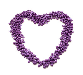 Wax for depilation of purple color in the shape of a heart. On white background. Close-up.