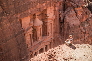 Traveler overlooking Ancient ruins among the red rocks of Petra, Jordan