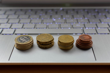 Cuatro grupos de monedas encima de un ordenador 