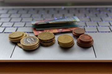Grupos de monedas y billetes encima de un ordenador 