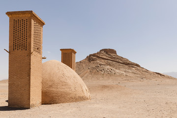Water reservoir and wind towers (badgirs) with Zoroastrian Tower of Silence in the background