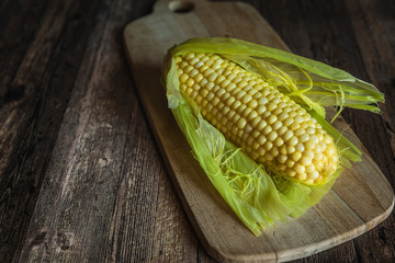 Corn on the cob on a wooden table. Sweet steamed corn on cutting board.