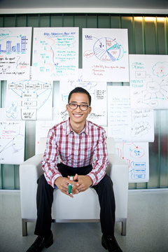 Portrait of smiling businessman sitting against charts in office