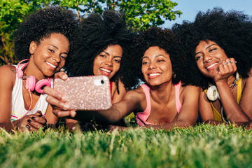 Afro women friends hanging out in the park using a cellphone