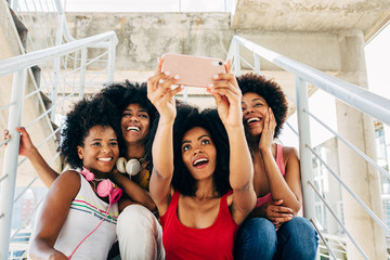 Afro women friends hanging out in the city using a cellphone