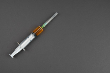 Corona virus vaccine concept: A syringe with a yellow substance  on black background, isolated and with copy space