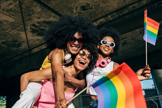 Afro women friends hanging out in the city waving LGBT