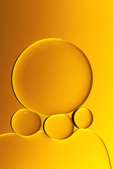 Macro photography of small drops of oil floating on water with yellow background. Abstract composition of great beauty. Background for design.