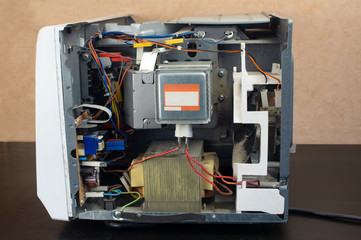 Repair of a microwave oven, repair of household appliances. Microwave with side panel removed, internal device visible