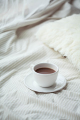 A cup of hot cocoa on the bed. Cozy. Homeliness.