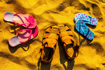 Warm summer. There are Slippers on the sand. three pairs.
