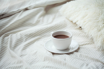 A cup of hot cocoa on the bed. Cozy. Homeliness.