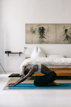 Black Woman Doing Yoga Pose in White Bedroom