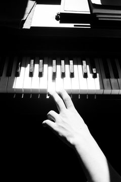 A beautiful black and white photo of hand of a young boy playing piano