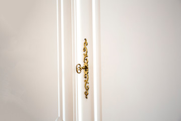White cupboard doors with Golden key in keyhole, luxury antique design close-up wooden vintage doors