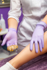 Obraz na płótnie Canvas Shugaring master makes the procedure on female leg