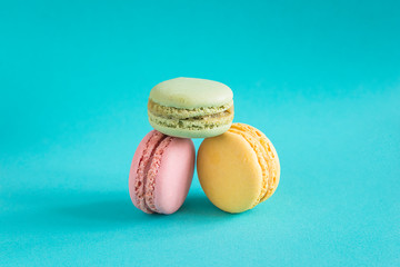 Three pink, yellow and green french macaroons on blue background. Close up