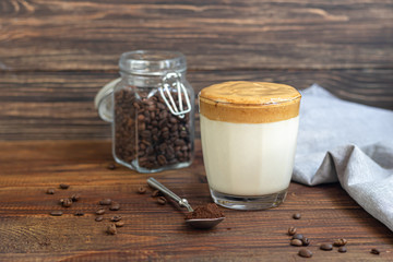 Dalgona coffee is a trendy cold Korean drink. Tasty, aromatic coffee with milk and sugar in a glass on a wooden background.