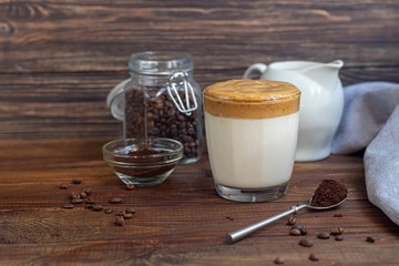 Dalgona coffee is a trendy cold Korean drink. Tasty, aromatic coffee with milk and sugar in a glass on a wooden background.