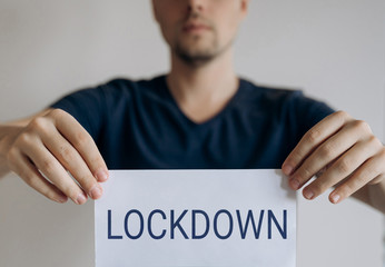 Man holds sheet with the word Lockdown. Pandemic of COVID-19. Coronavirus quarantine isolation concept. Stay at home