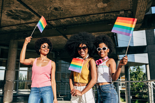 Afro women friends hanging out in the city waving LGBT