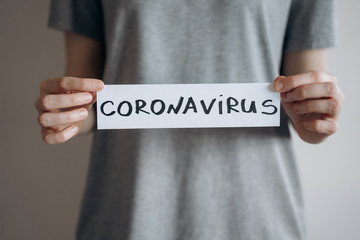 Woman holds sheet with word Coronavirus. Pandemic of COVID-19. Coronavirus quarantine isolation concept. Stay at home