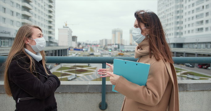 Epidemic Control Social Care Workers. Two Young Caucasian Female Social Care Employees In Face Masks Talk Outside.