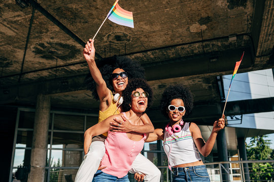 Afro women friends hanging out in the city waving LGBT