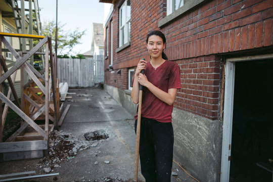 Dirty, hard-working woman looking at the camera with shovel.