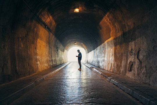 Silhouette of man addicted to the phone in a dark tunnel
