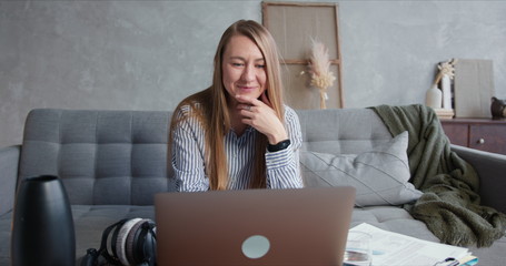 Working from home on quarantine. Young stressed blonde business woman smiles using laptop for video...