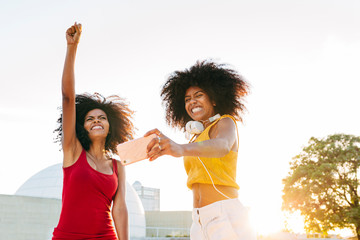 Afro women friends hanging out in the city using a cellphone