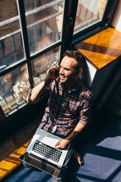 Young man having a conversation on cellphone while looking through the window