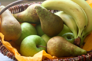 Basket with bananas, apples, pears and lemons. Selective focus.