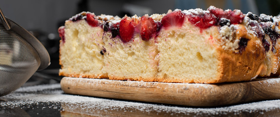 strawberry yeast cake covered with powdered sugar on wooden board
