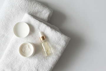 Oil serum essence dropper and moisturizer cream on towels on white background with copy space....