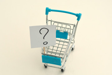 Paper stickers with a question mark in a mini shopping trolley. Concept for solving the problem